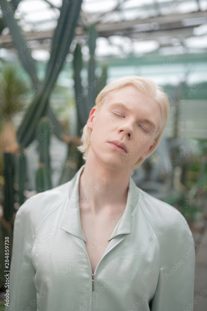 Male model closing eyes while posing in greenhouse Male model closing eyes while posing in greenhouse