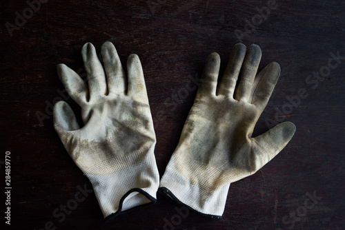 old dirty textile work gloves on dark wooden background