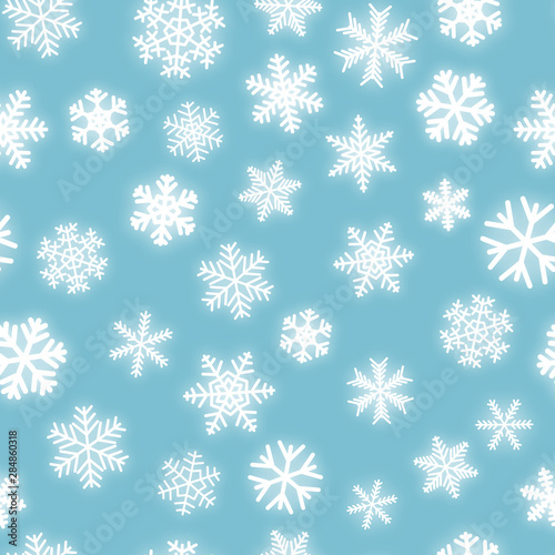 Christmas seamless pattern of white snowflakes of different shapes on light blue background
