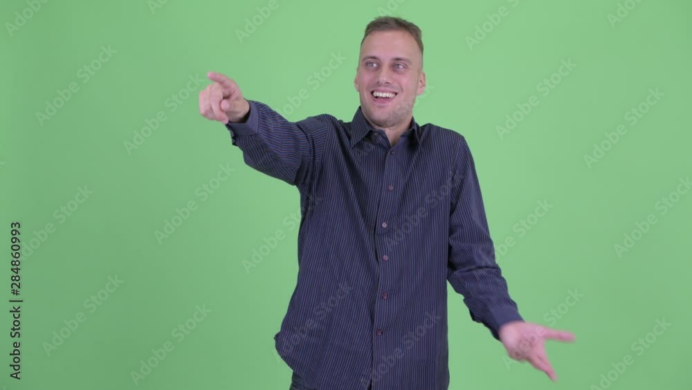 Happy handsome businessman pointing finger and looking surprised Happy handsome businessman pointing finger and looking surprised