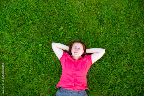 Portrait of a smiling red-haired young girl on green grass