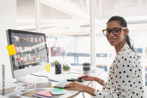 Female graphic designer using graphic tablet at desk in office