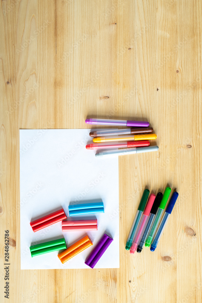 Fototapeta premium Overview of wooden table background with blank paper and crayons