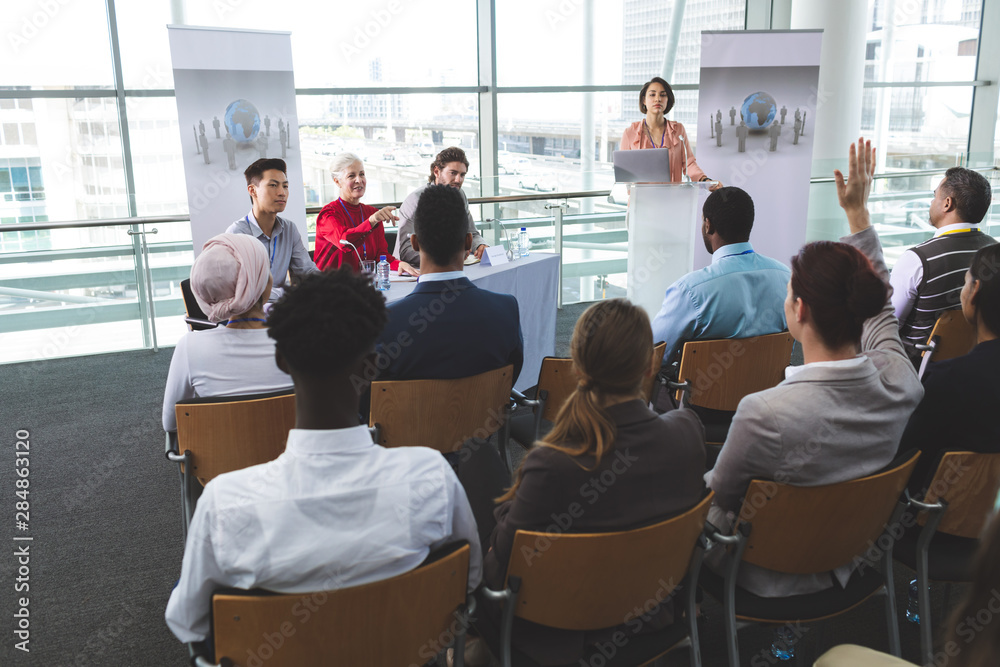 Businesswoman raising hand in a business seminar