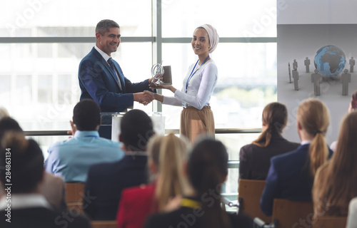 Businesswoman receiving award from businessman in a business seminar 