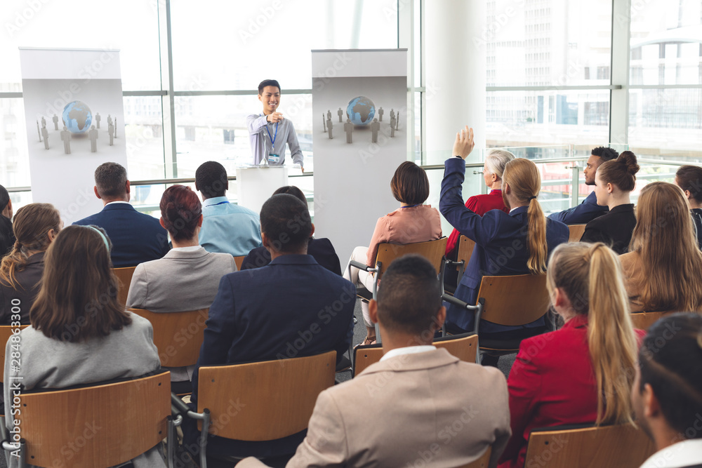 Obraz premium Businessman raising hand in a business seminar