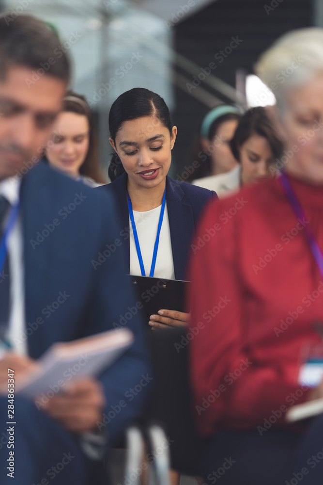 Obraz premium Young businesswoman writing on notepad in a business seminar