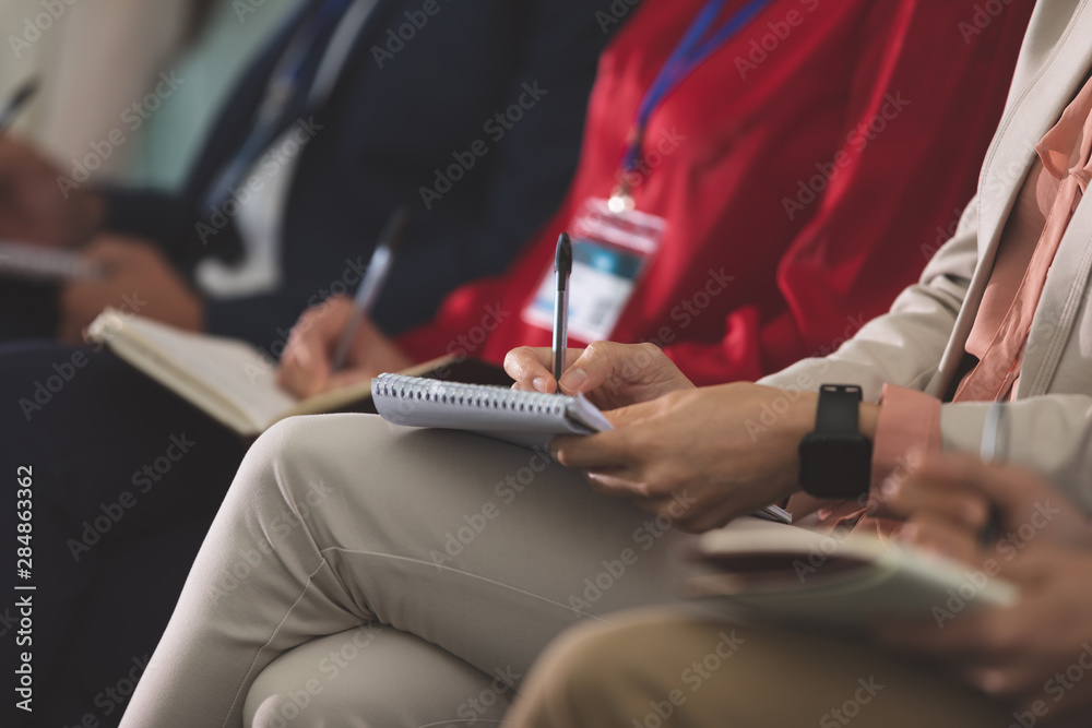 Business people writing on notepad in a business seminar