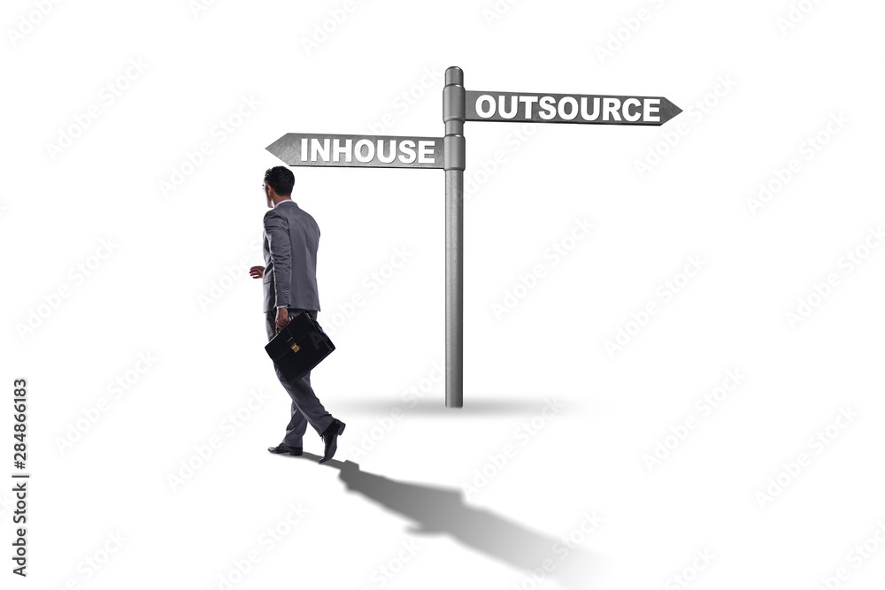 Businessman at crossroads deciding between outsourcing and inhou Businessman at crossroads deciding between outsourcing and inhou