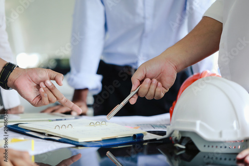 The hands of two men at the meeting are discussing the design of the house.