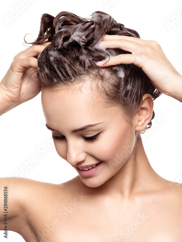 Beautiful smiling woman soaping the hair
