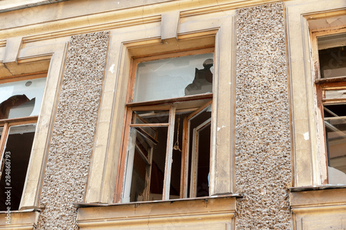 broken glass in the windows of an old settled and abandoned town house