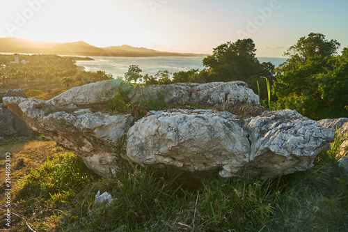 A huge stone on the ocean coast with a resort settlement in the background photo