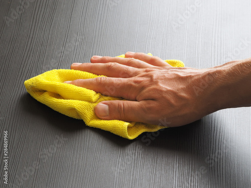 a man rubs a table with a microfiber rag.