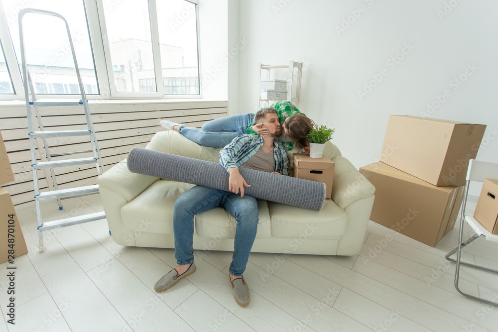 Cheerful young couple rejoices in moving to a new home laying out their belongings in the living room. Concept of housewarming and mortgages for a young family Cheerful young couple rejoices in moving to a new home laying out their belongings in the living room. Concept of housewarming and mortgages for a young family