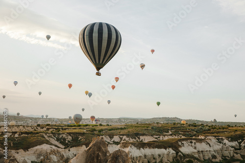 Goreme, Turkey / May, 2019 - Numerous hot air balloons all lift into the air just after dawn