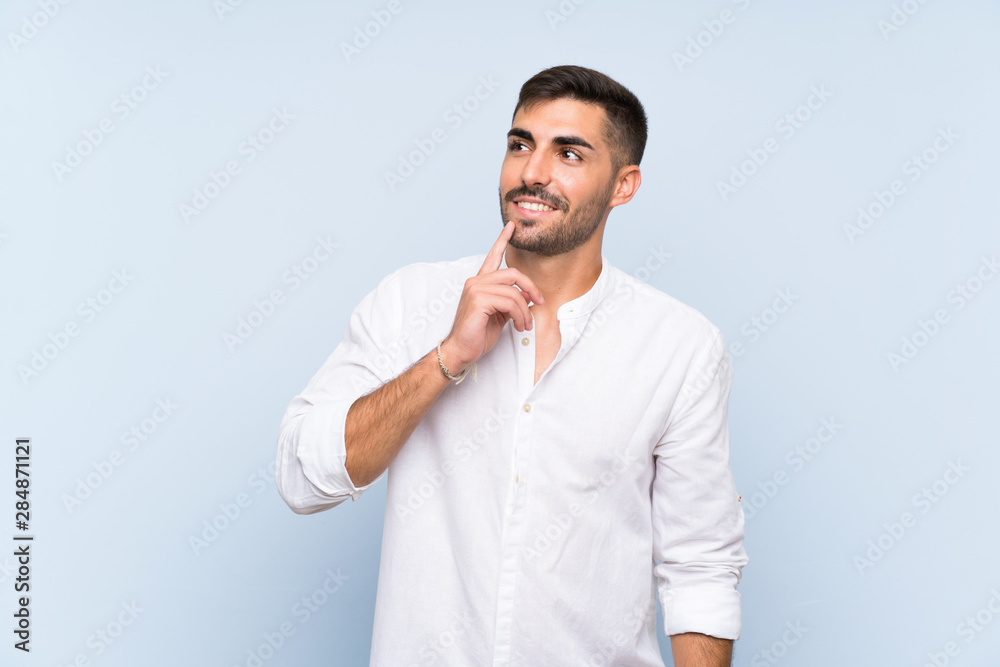 Handsome man with beard over isolated blue background thinking an idea while looking up Handsome man with beard over isolated blue background thinking an idea while looking up