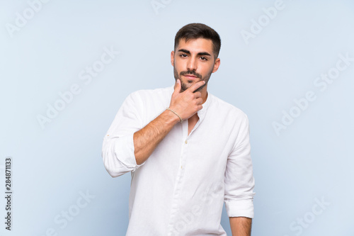 Handsome man with beard over isolated blue background thinking