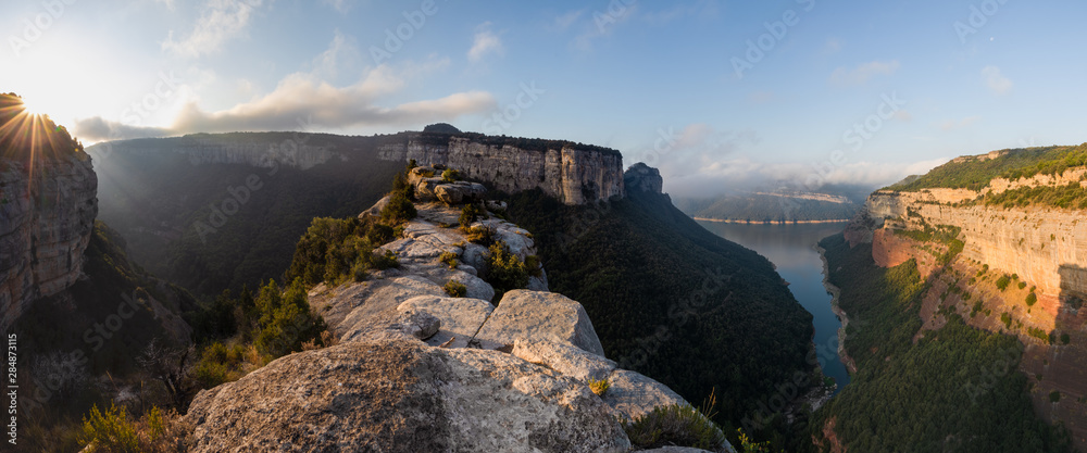 Panoramic of a high altitude mountainous area with stone walls and lake at the bottom of the valley