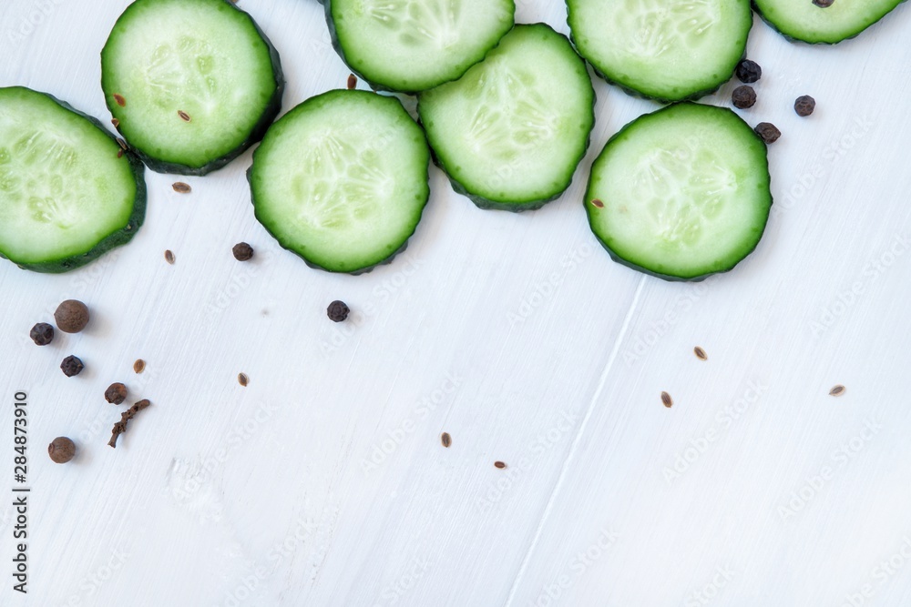 Slices of fresh cucumber and spices. Close-up on a white wooden background. Slices of fresh cucumber and spices. Close-up on a white wooden background.