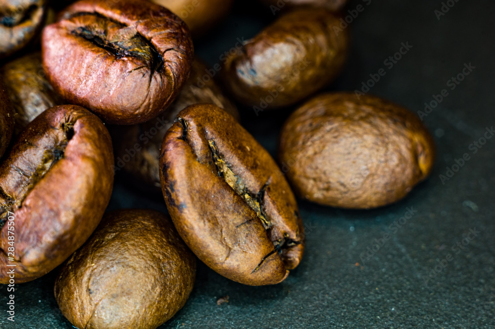 Brown roasted coffee beans on black background, close up, macro Brown roasted coffee beans on black background, close up, macro