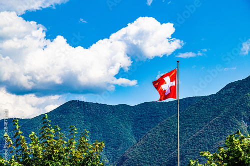 Switzerland flag waving on the wind. Mountains and clouds in the background