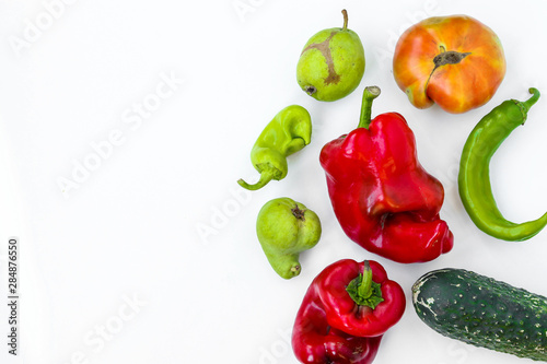 Trendy Ugly Organic Vegetables: pears, cucumber, peppers, chili and tomato on white background, ugly food concept, horizontal orientation, copy space