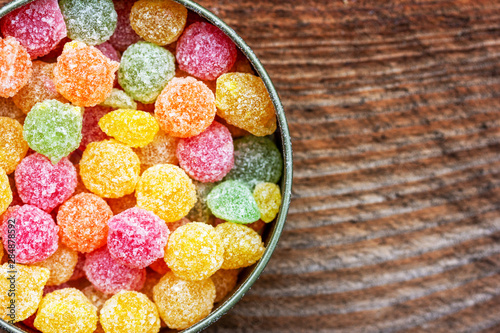 colorful multicolored sucking sweets Montpensier lollipops in a round tin box on a wooden background close-up with copy space, top view photo