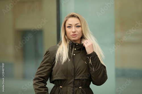 Outdoors lifestyle fashion portrait of happy stunning blonde girl. Beautiful smile. Walking to the city street. Joyful and cheerful woman. Happiness.