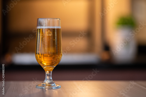 Not branded glass of golden beer on the table, barbecue grill on background