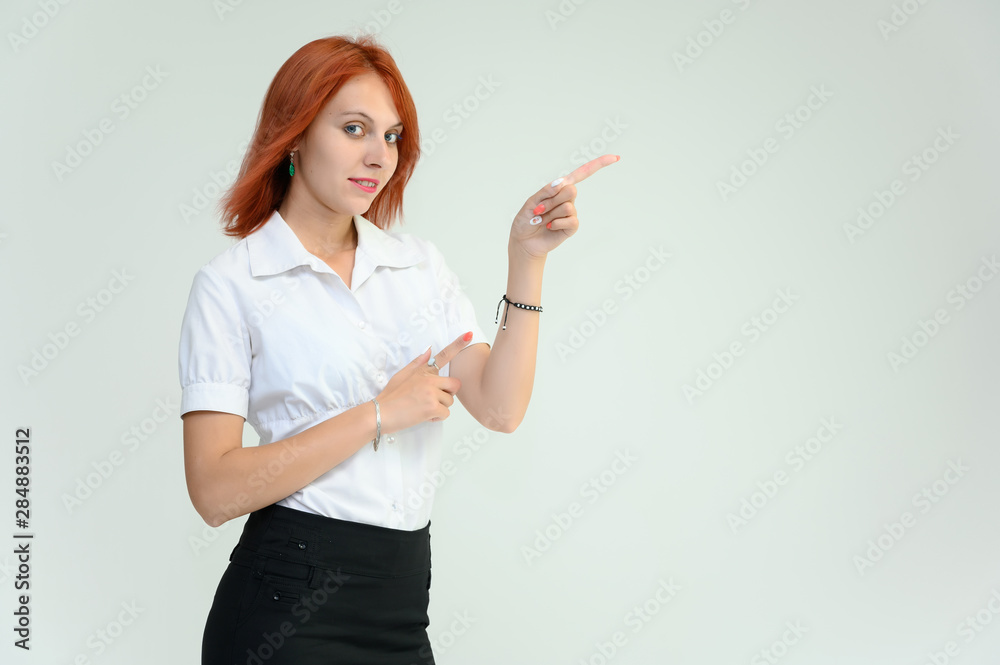 Photo Portrait of a cute girl woman with bright red hair manager in a white shirt on a white background in studio. He talks, shows his hands in front of the camera with emotions. Photo Portrait of a cute girl woman with bright red hair manager in a white shirt on a white background in studio. He talks, shows his hands in front of the camera with emotions.