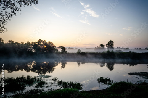 Fog rises over the river during sunrise. Morning fog