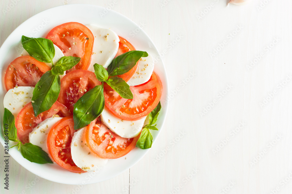 Close-up photo of caprese salad with ripe tomatoes, basil, buffalo mozzarella cheese. Italian and Mediterranean food concept. Fresh and healthy organic meal. Starter and antipasti. Close-up photo of caprese salad with ripe tomatoes, basil, buffalo mozzarella cheese. Italian and Mediterranean food concept. Fresh and healthy organic meal. Starter and antipasti.