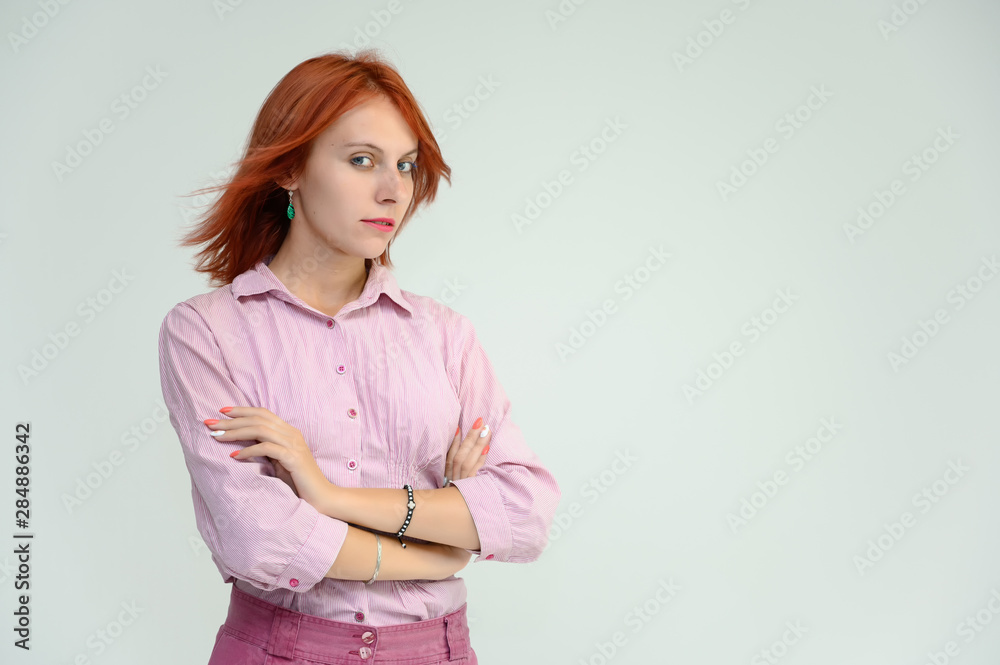 Photo Portrait of a cute girl woman with bright red hair manager in a pink shirt on a white background in studio. He talks, shows his hands in front of the camera with emotions. Photo Portrait of a cute girl woman with bright red hair manager in a pink shirt on a white background in studio. He talks, shows his hands in front of the camera with emotions.