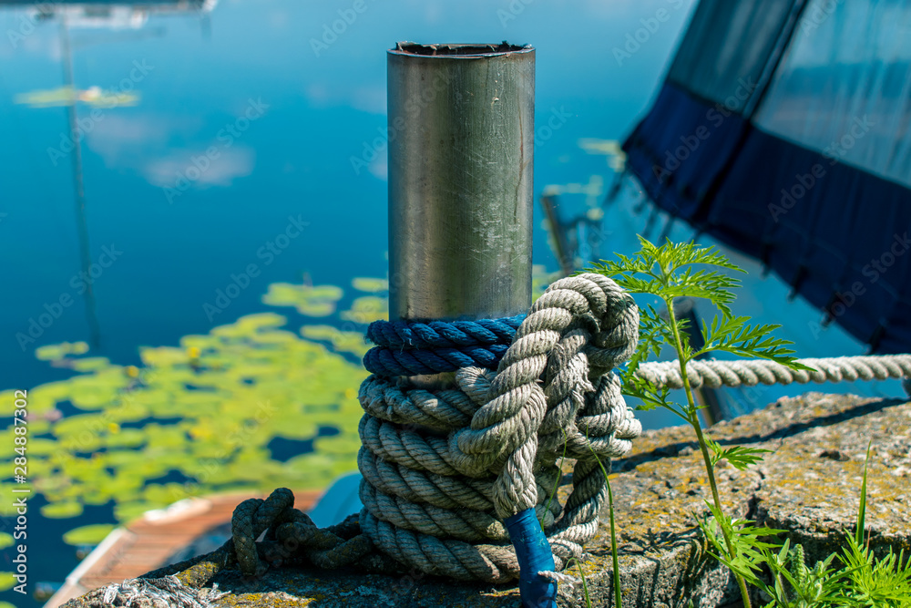 Fototapeta premium Bollard for mooring tied with a rope. Knecht on the pier for fastening ropes