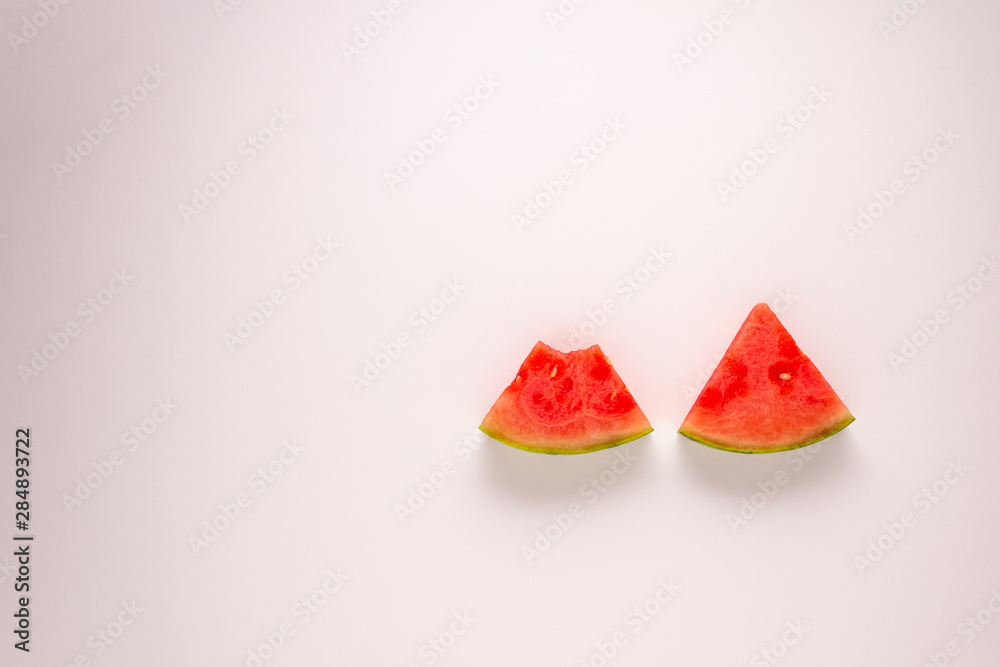 Two slices of water melon with a bite take out of one against a white background