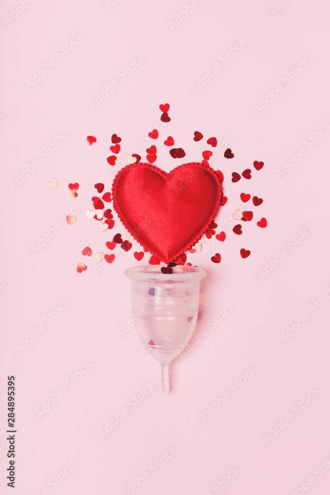 Transparent menstrual cup with red hearts on a grey background