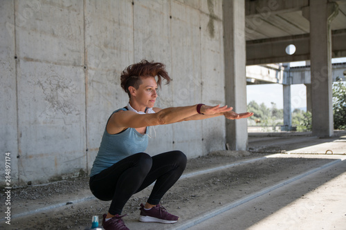 Young attractive sportswoman doing exercises at old abandoned concrete factory