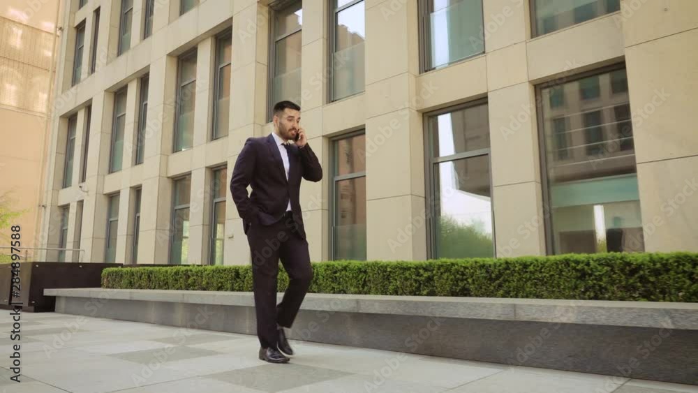 Emotional smiling young man talking on smartphone outdoor. Excited businessman happy to hear good news while talking on cell phone Emotional smiling young man talking on smartphone outdoor. Excited businessman happy to hear good news while talking on cell phone