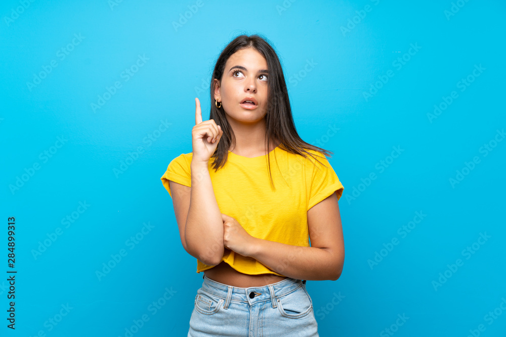 Young girl over isolated blue background thinking an idea pointing the finger up Young girl over isolated blue background thinking an idea pointing the finger up