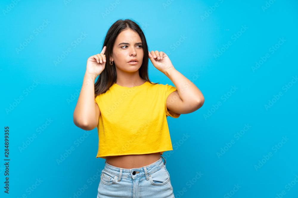 Fototapeta premium Young girl over isolated blue background having doubts and thinking