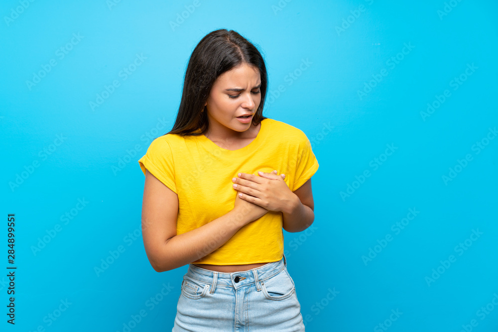 Young girl over isolated blue background having a pain in the heart Young girl over isolated blue background having a pain in the heart