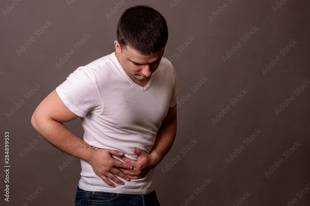Abdominal pain. A young guy holds his stomach. Abdominal pain. A young guy holds his stomach.