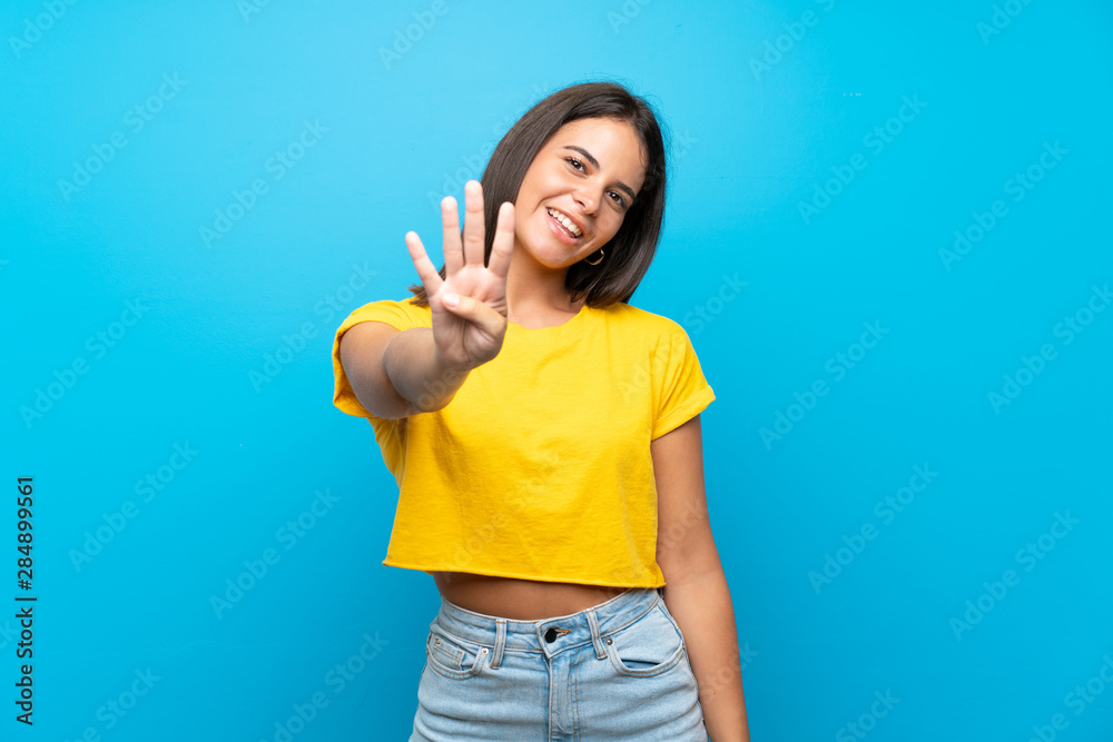 Young girl over isolated blue background happy and counting four with fingers Young girl over isolated blue background happy and counting four with fingers