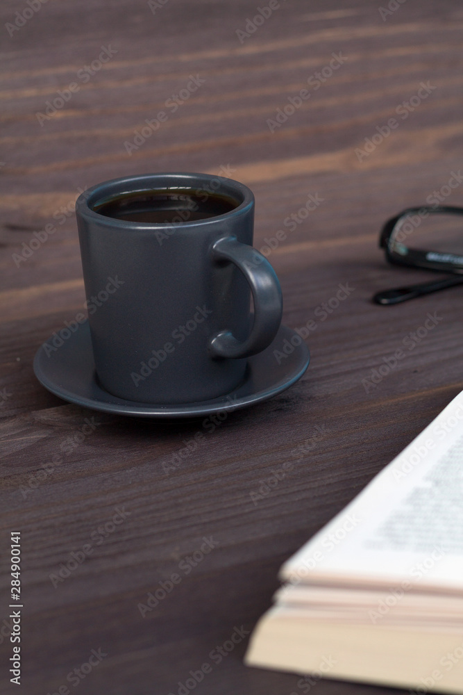 dark cup of coffee with book on wooden table dark cup of coffee with book on wooden table