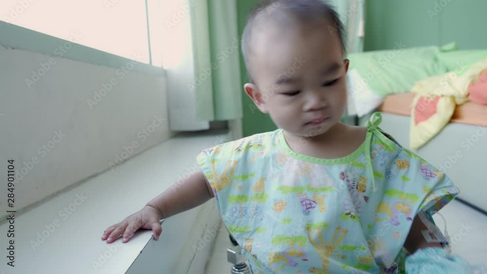 Asian baby boy playing and patient hand drip receiving a saline solution at the hospital Asian baby boy playing and patient hand drip receiving a saline solution at the hospital