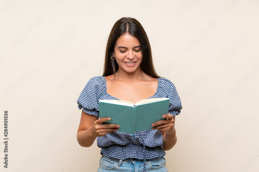 Young girl over isolated background holding and reading a book