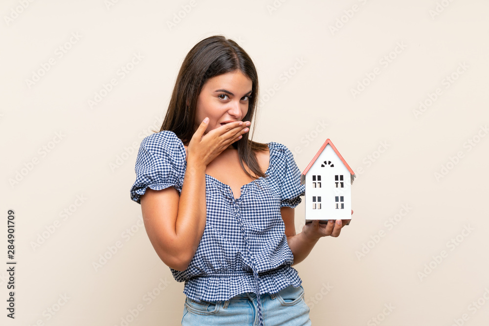 Young girl over isolated background holding a little house