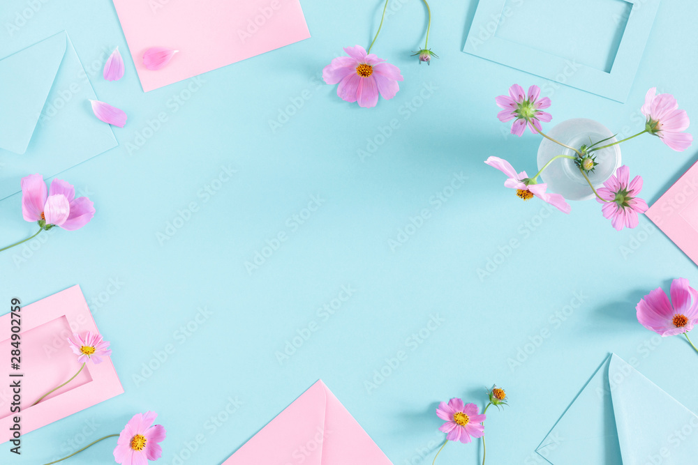Flowers composition romantic. Pink cosmos flowers, pink and blue envelopes on pastel blue background. Flat lay, top view, copy space