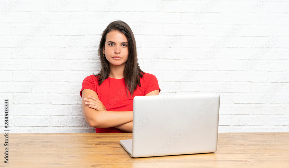 Young girl with pc in a table keeping arms crossed